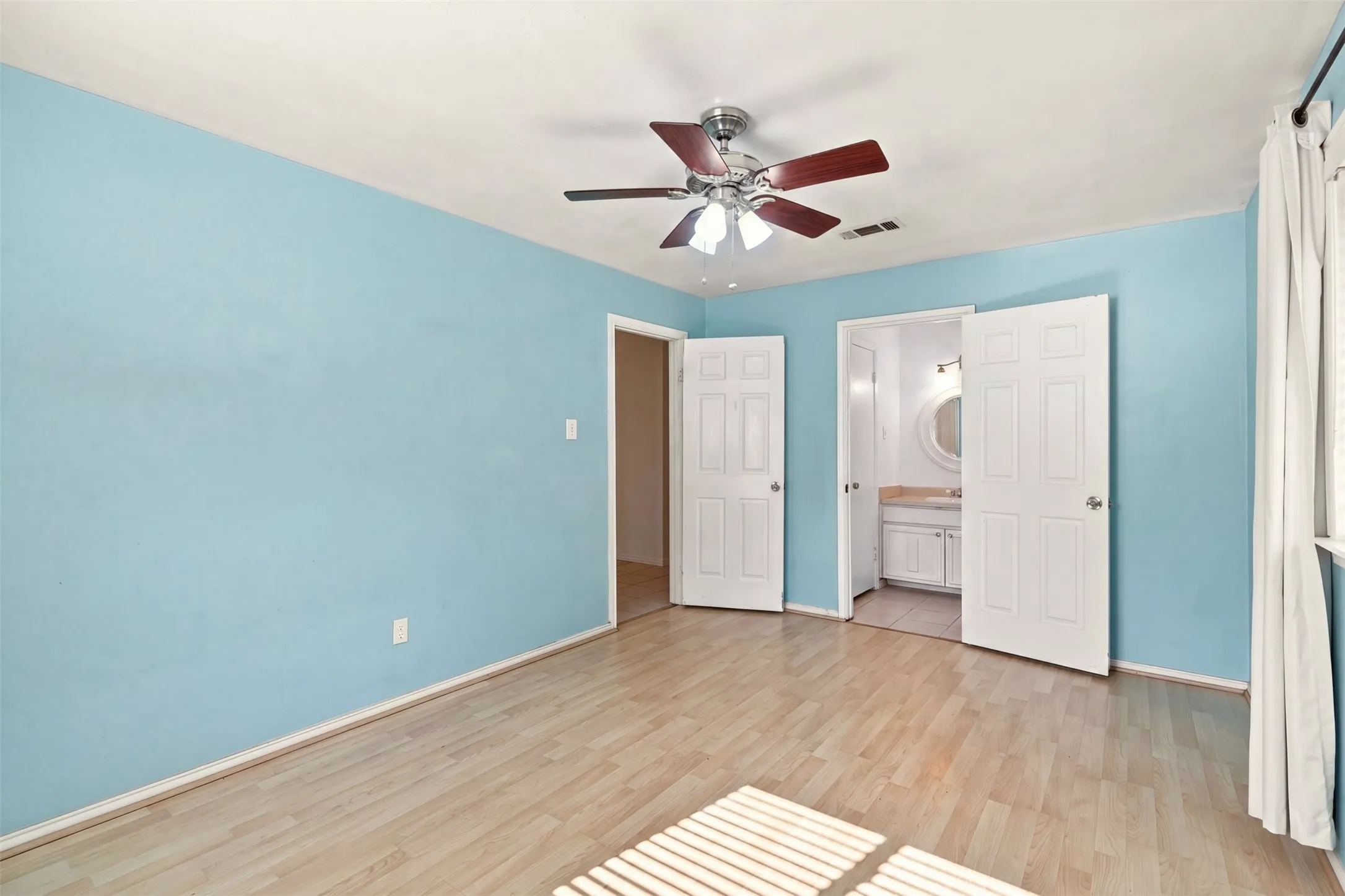 Wood-finish flooring with a ceiling fan and recessed lighting