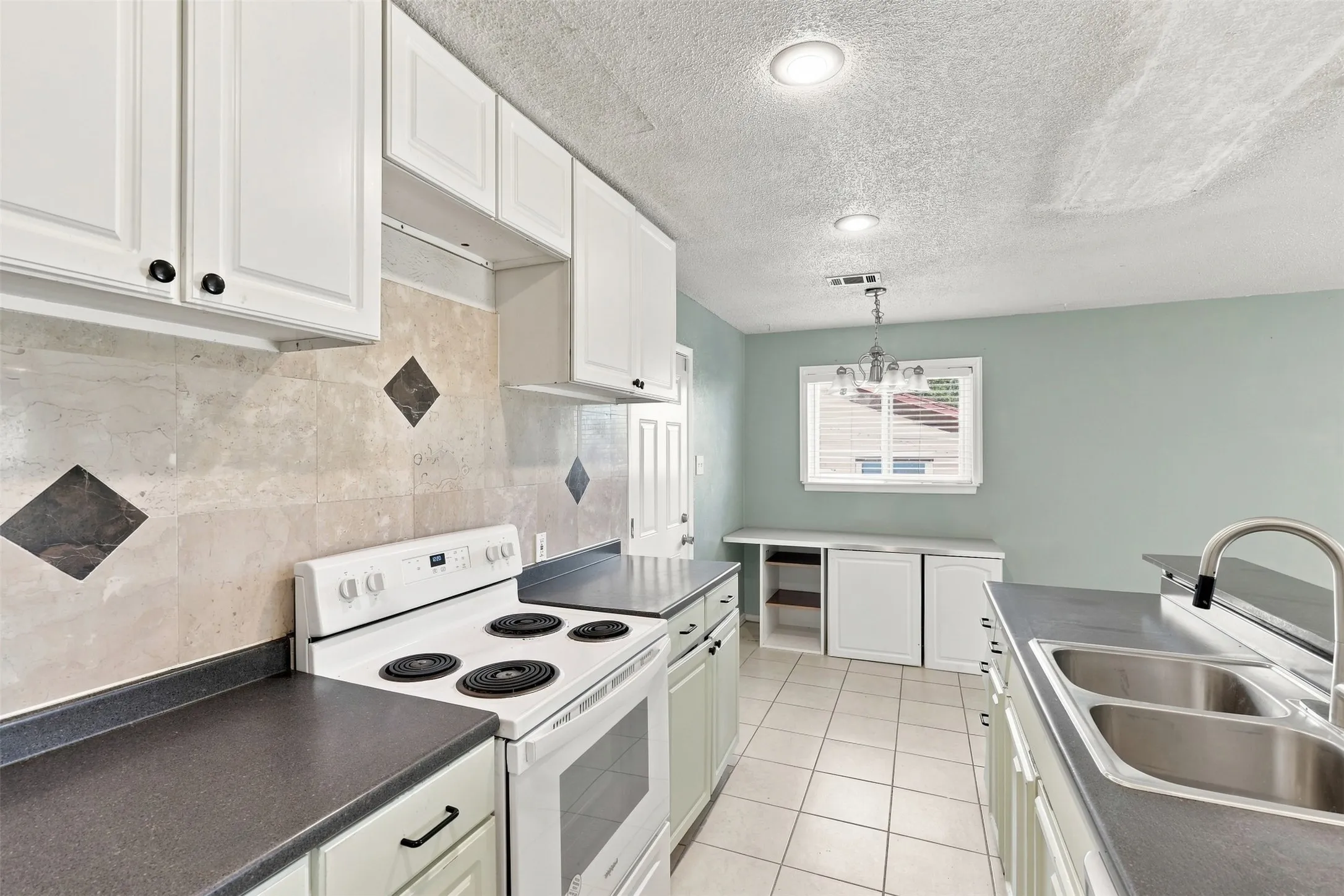 White cabinetry, tile flooring, dual basin stainless steel sink, built-in window seating, and recessed lighting