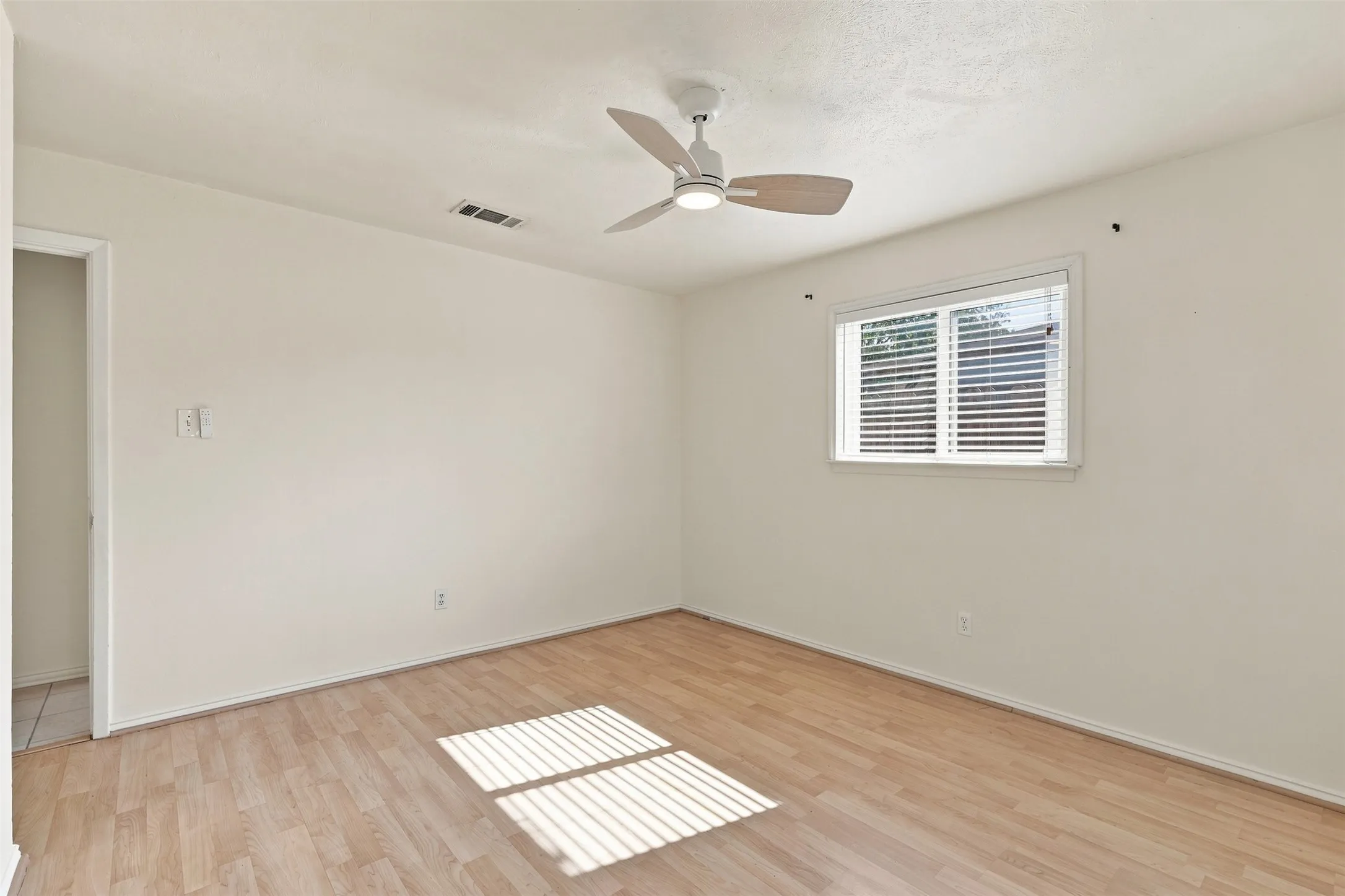 Wood-finish flooring, white walls, and a ceiling fan with integrated lighting