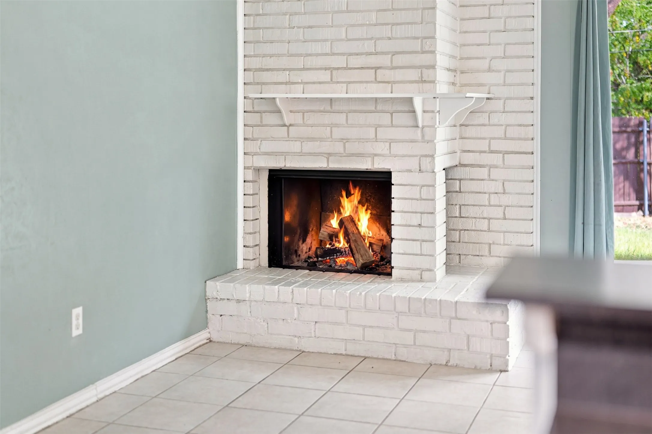 White-painted brick fireplace with a raised hearth, a black firebox, and a white mantel shelf