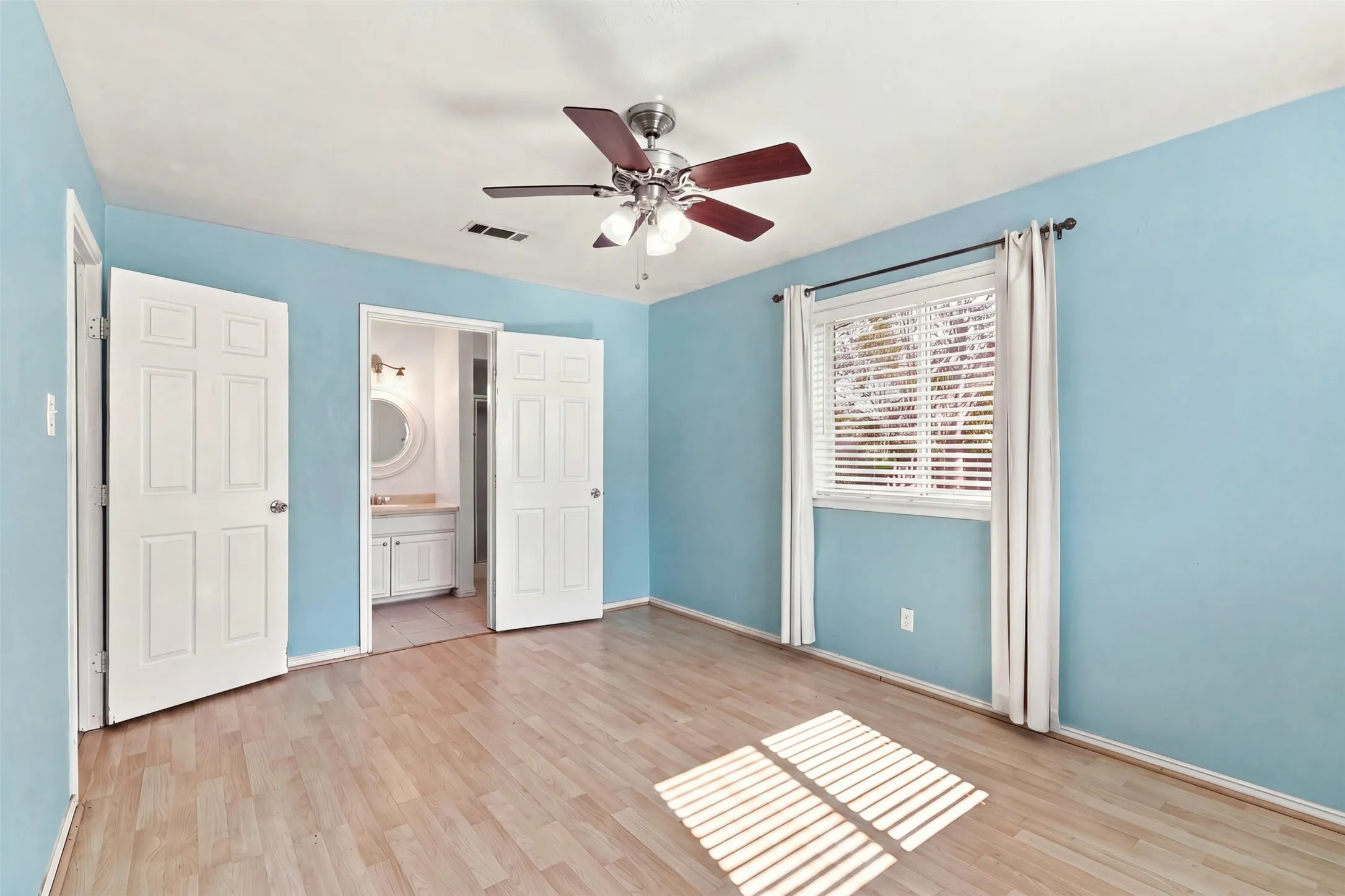 Wood-finish flooring, ceiling fan, window with blinds, and white panel doors