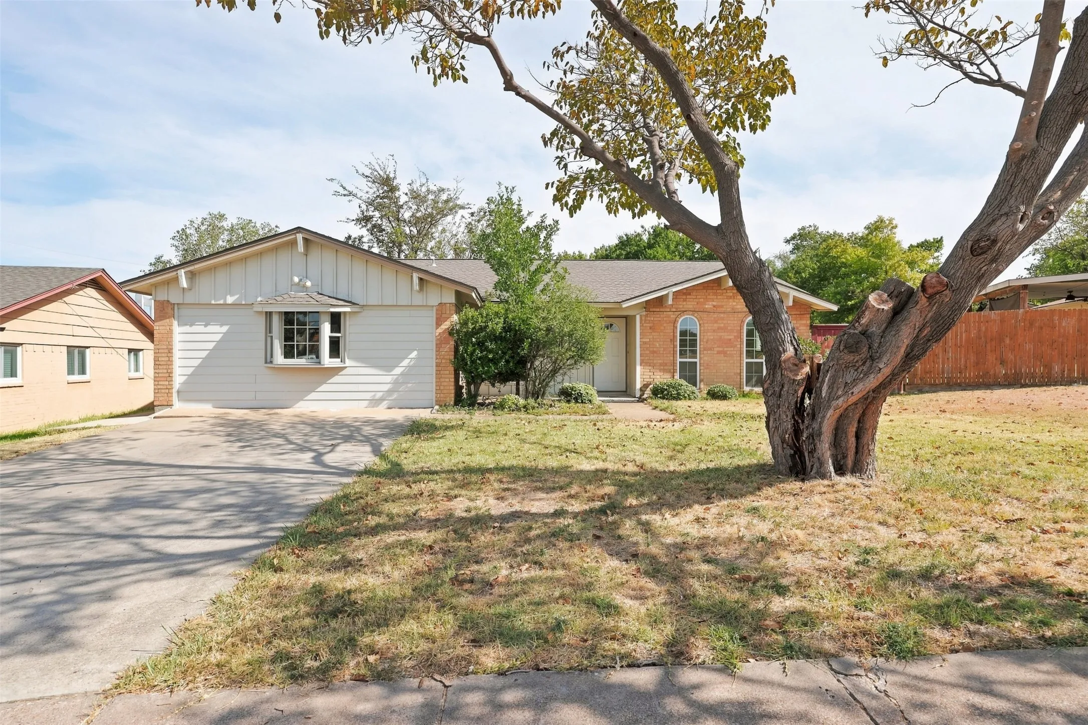 Single-story residence featuring a brick facade, bay window, and a two-car concrete driveway