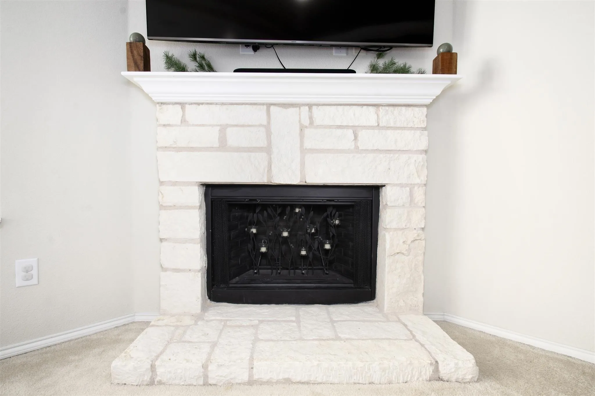 White stone-clad fireplace featuring a black firebox and a substantial white mantel