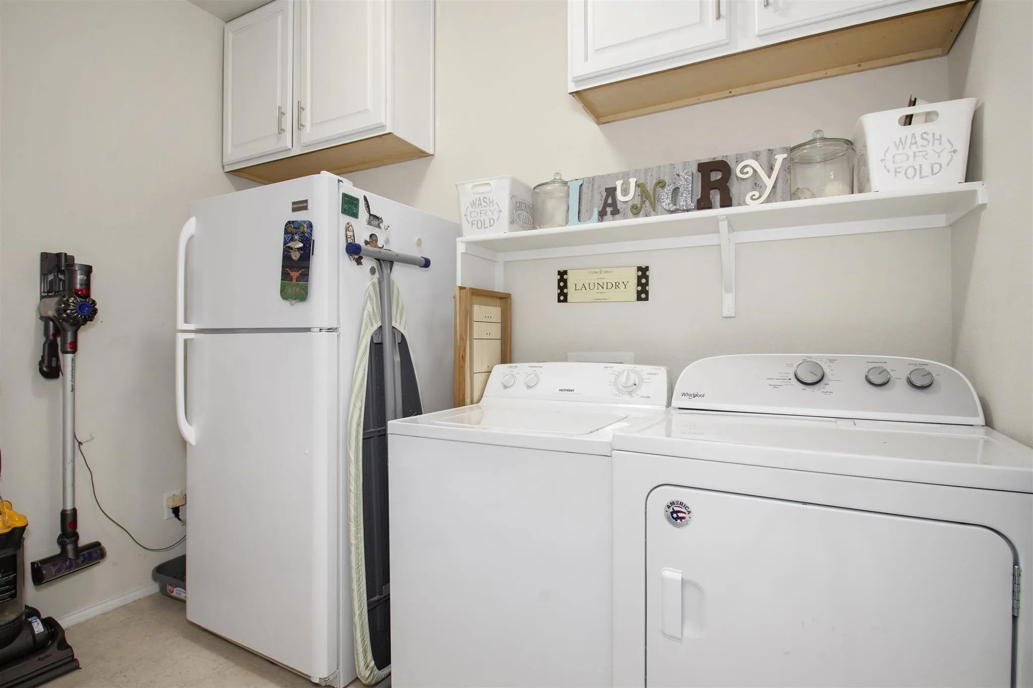White wall-mounted cabinetry and an open shelf provide storage
