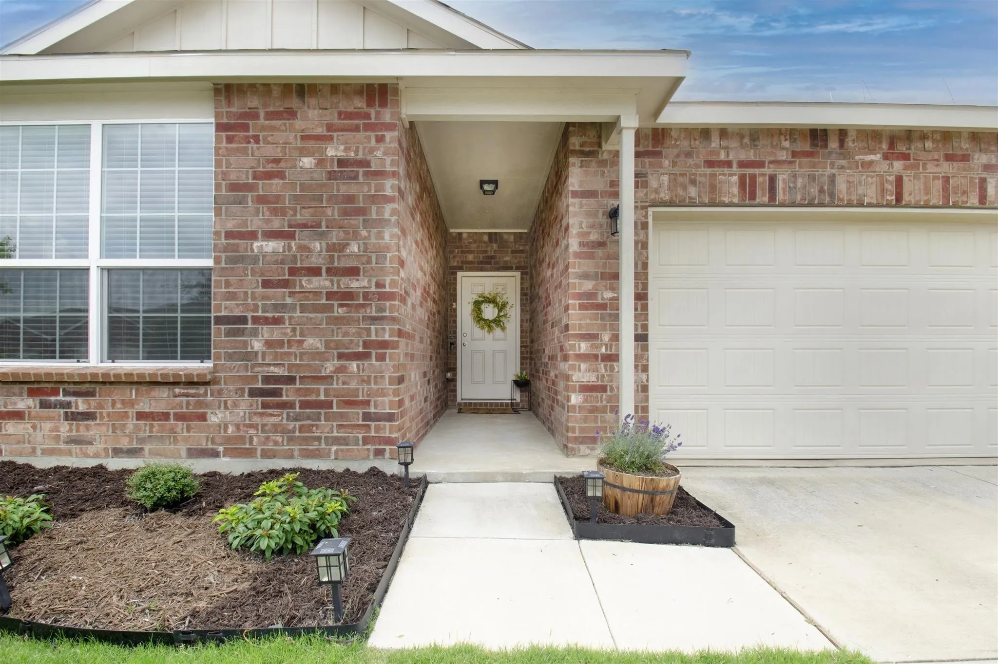 Brick exterior with white trim, an attached garage, and a covered entry