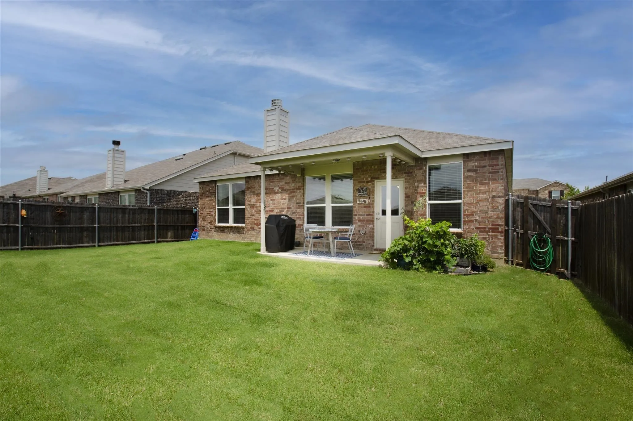 Expansive grassy backyard featuring a paved patio and a covered porch