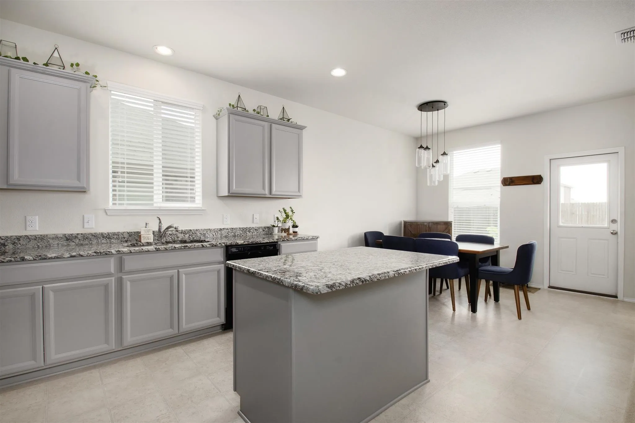 Recessed lighting illuminates the kitchen, featuring light gray cabinetry and granite-style countertops