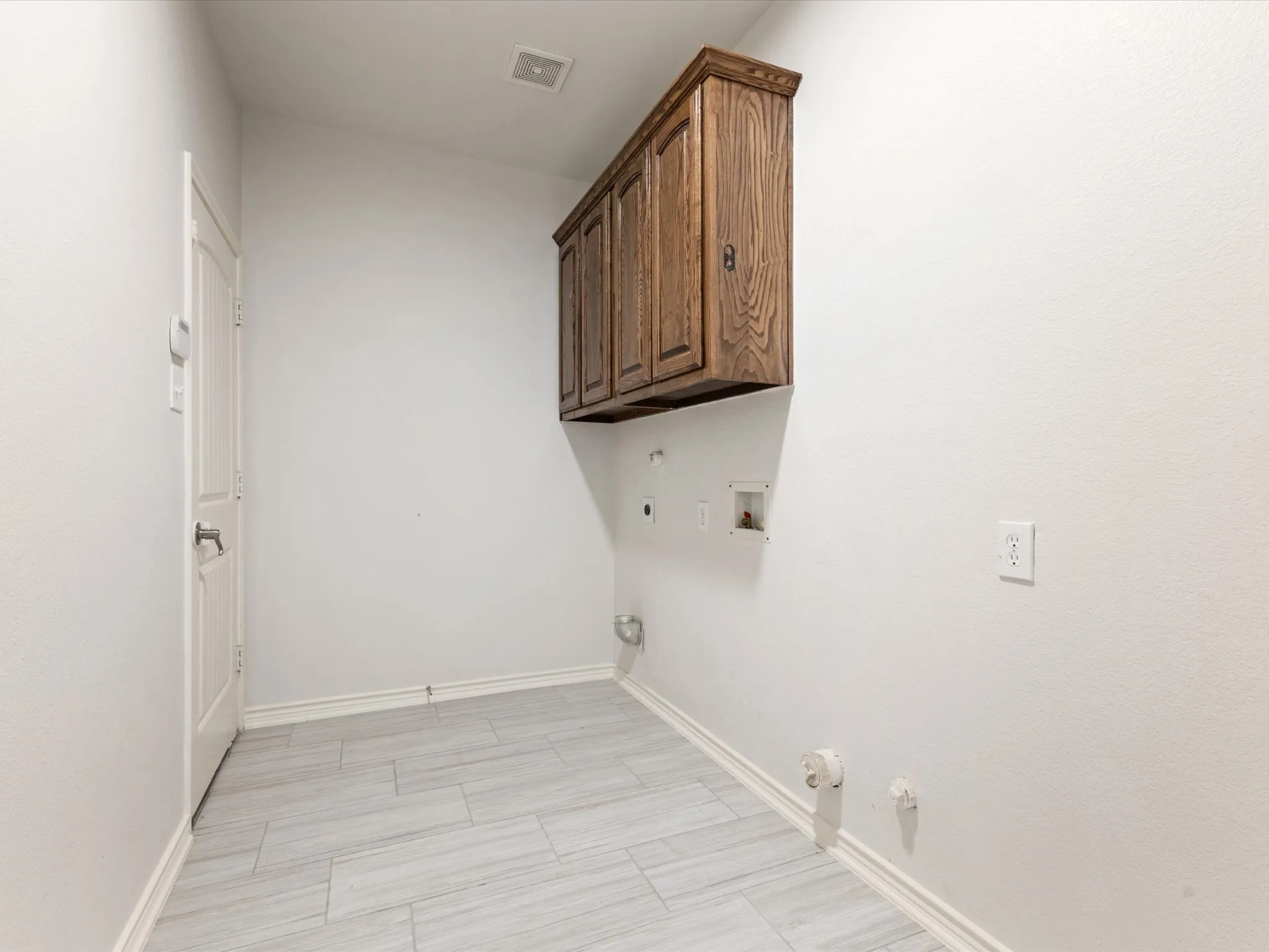Wood cabinetry, light-toned wall paint, and light gray tile flooring