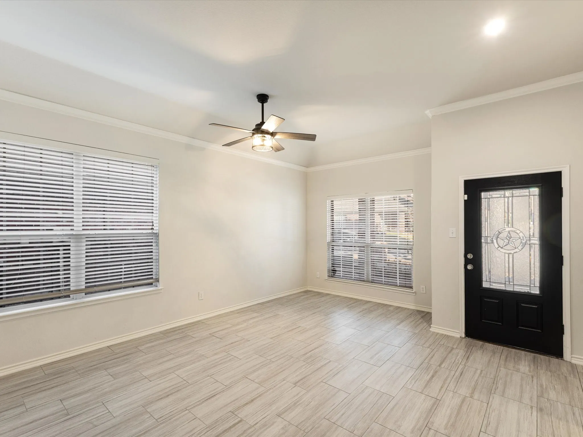 Vaulted ceiling, ceiling fan with integrated lighting, tile flooring, crown molding, and decorative glass front door