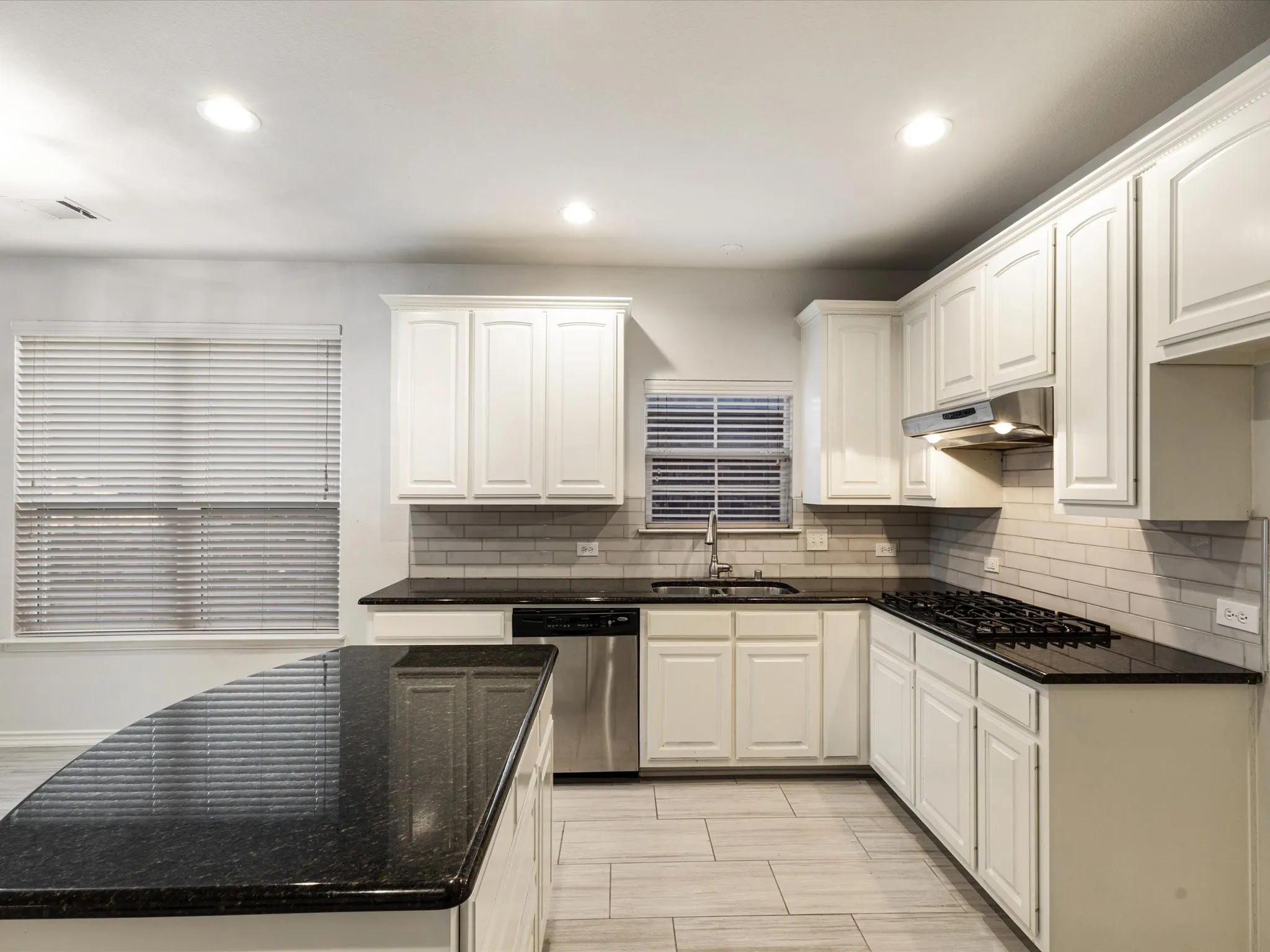 Kitchen featuring white cabinetry, dark stone countertops, tile backsplash, stainless steel appliances, and tile flooring