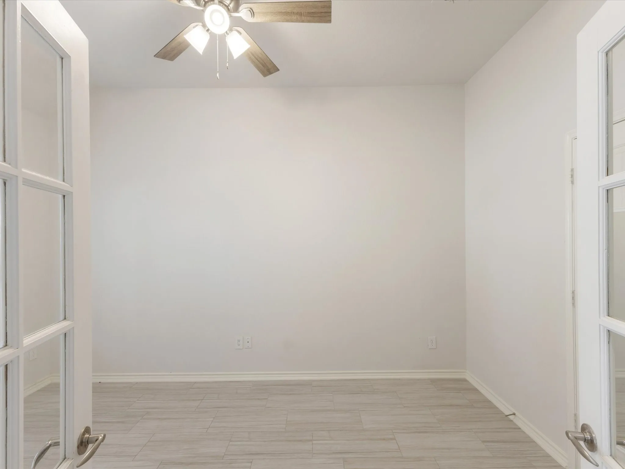 Light gray wood-look flooring, ceiling fan with integrated lighting, and white walls