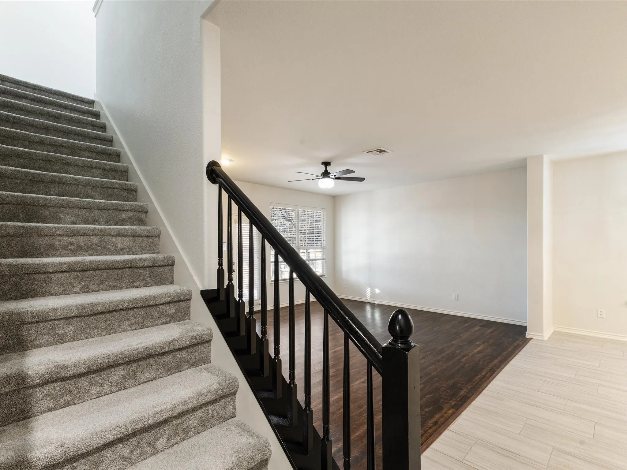 Carpeted staircase with dark wood-finish handrails and balusters