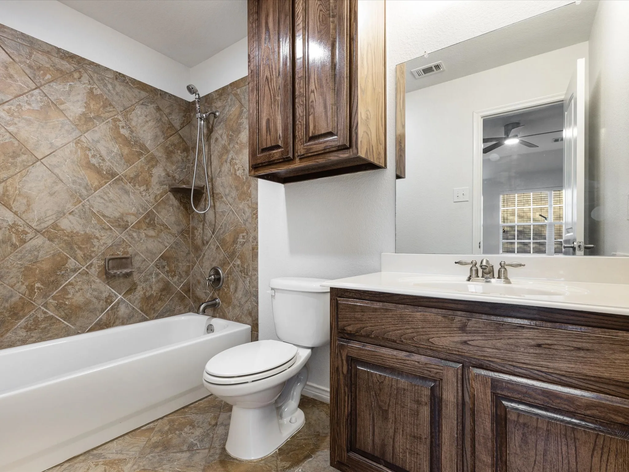 Spa-inspired bathroom featuring a wood-finish vanity with dual-sink configuration, quartz countertop, and chrome fixtures