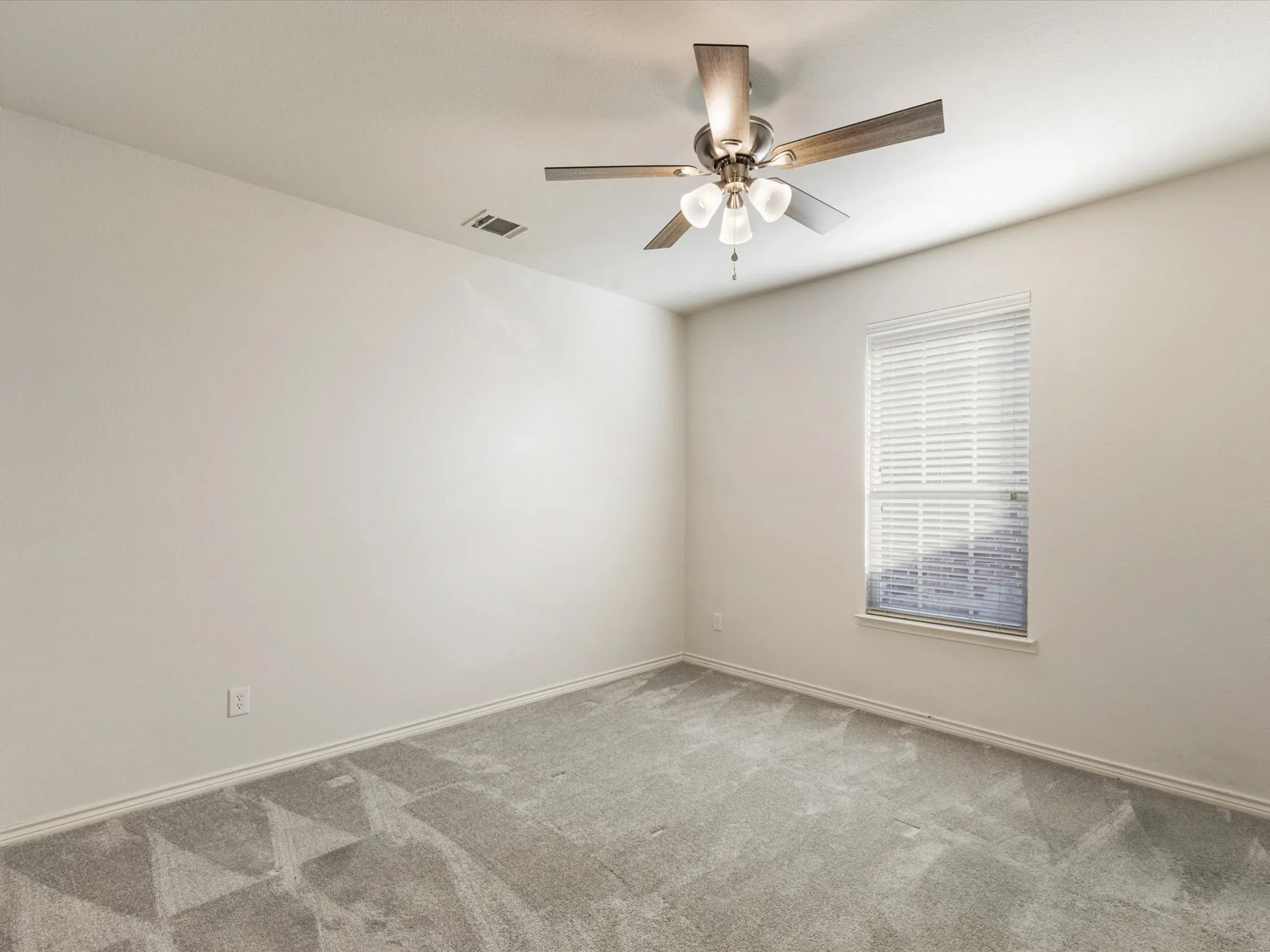 Ceiling fan with integrated lighting, window with blinds, light gray carpet, and neutral wall tones