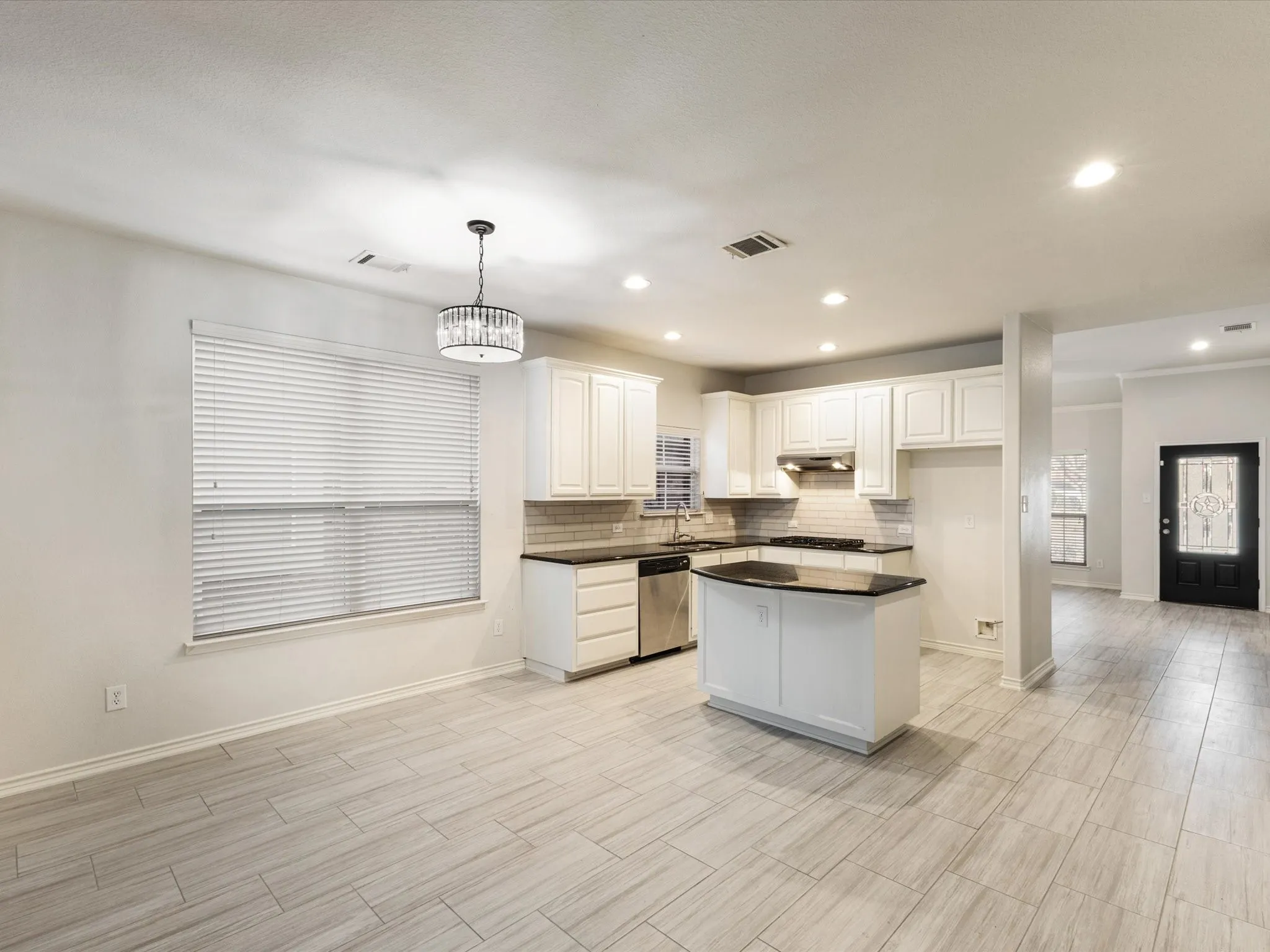 Kitchen featuring white cabinetry, dark countertops, a central island, stainless steel appliances, and a tile backsplash