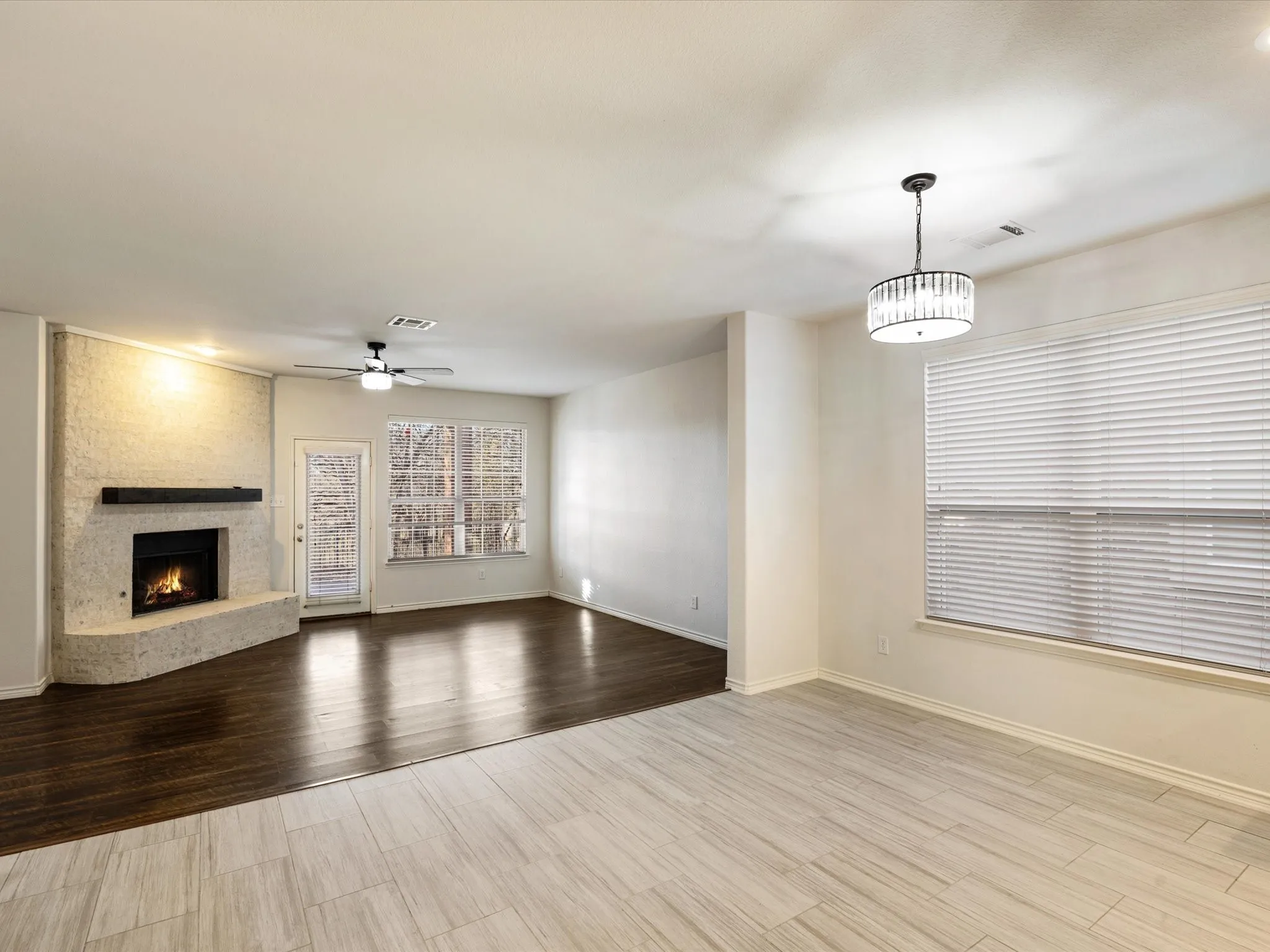 Textured fireplace with a dark wood-finish mantel, wood-finish flooring, and light-toned plank-style tile flooring