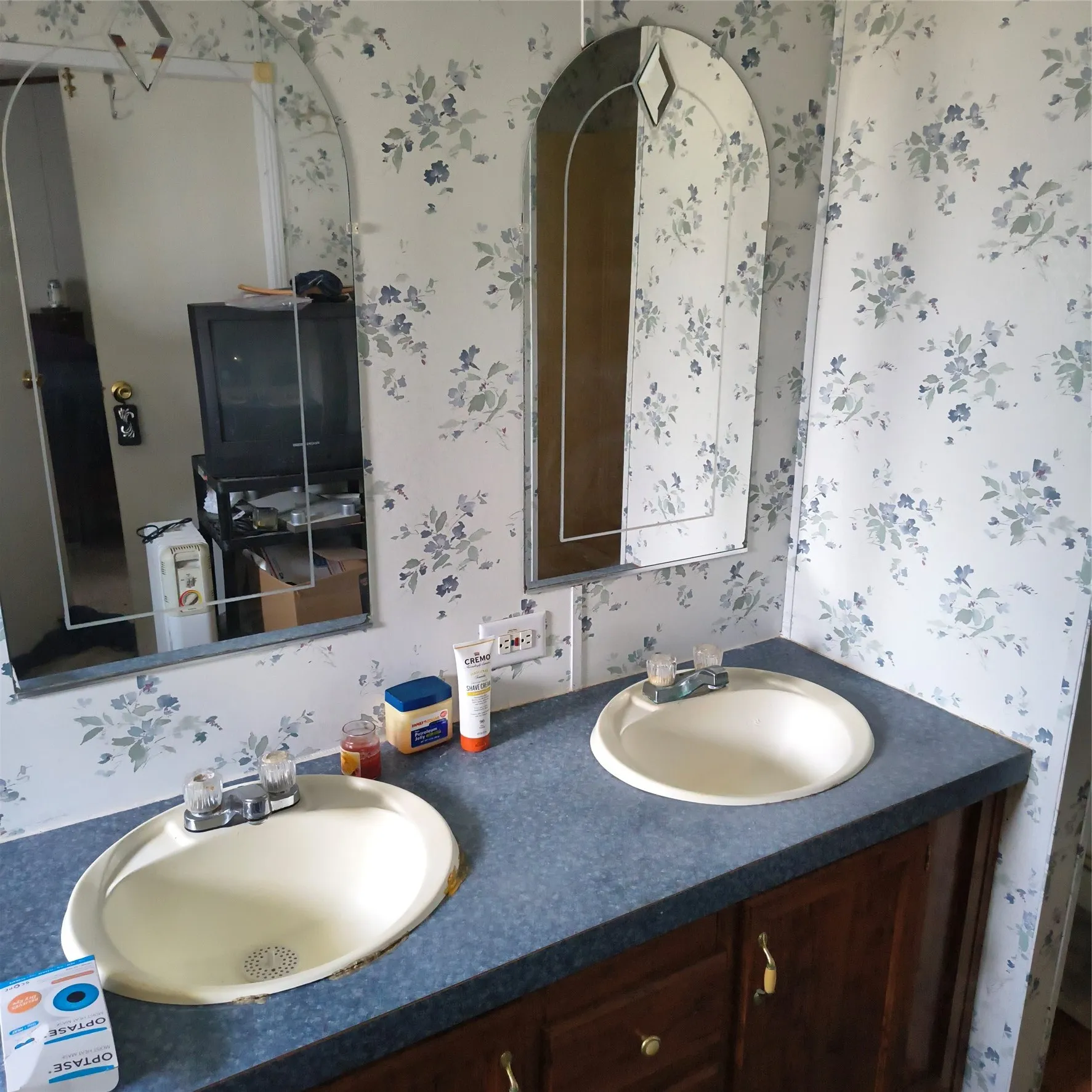 Dual vanity with integrated sinks, wood-finish cabinetry, and patterned wall covering