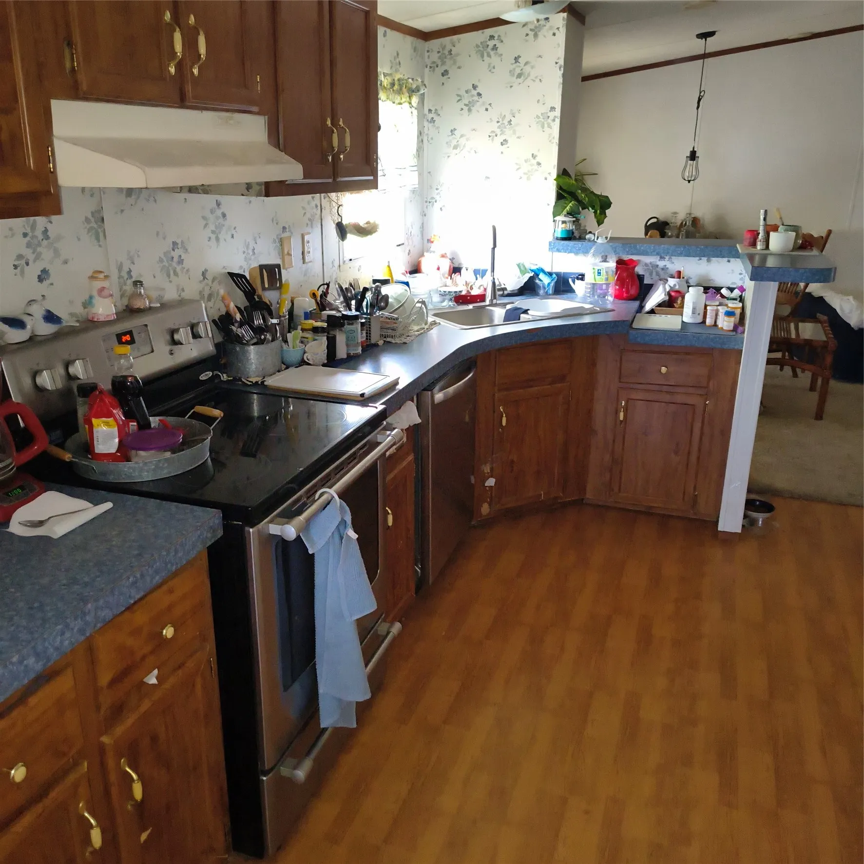 Wood-finish flooring, stainless steel range, stainless steel dishwasher, wood cabinetry, and a dual-basin sink