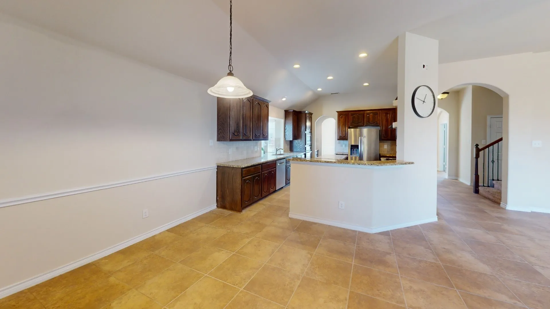 Open-concept kitchen with dark wood cabinetry, stainless steel appliances, and light-toned countertops