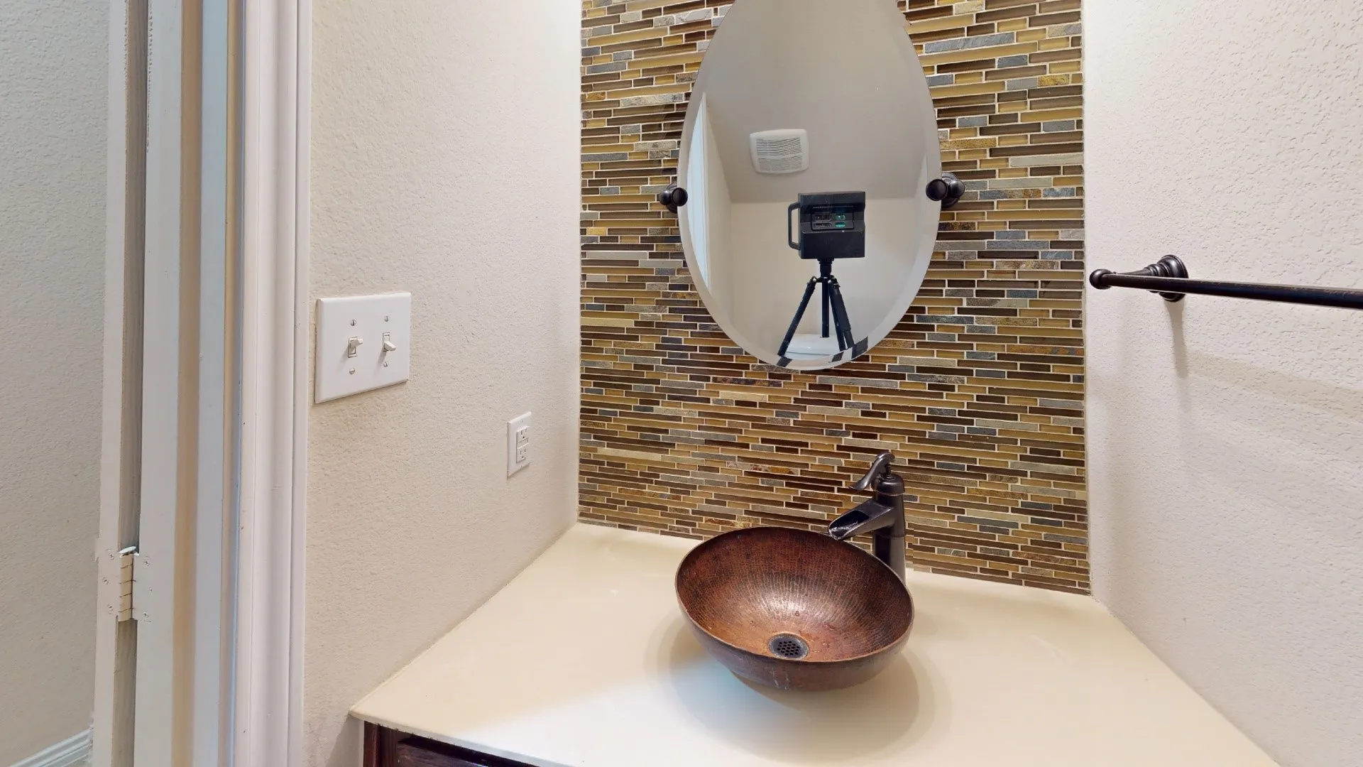 Copper vessel sink, oil-rubbed bronze faucet, oval mirror, and a mosaic tile backsplash