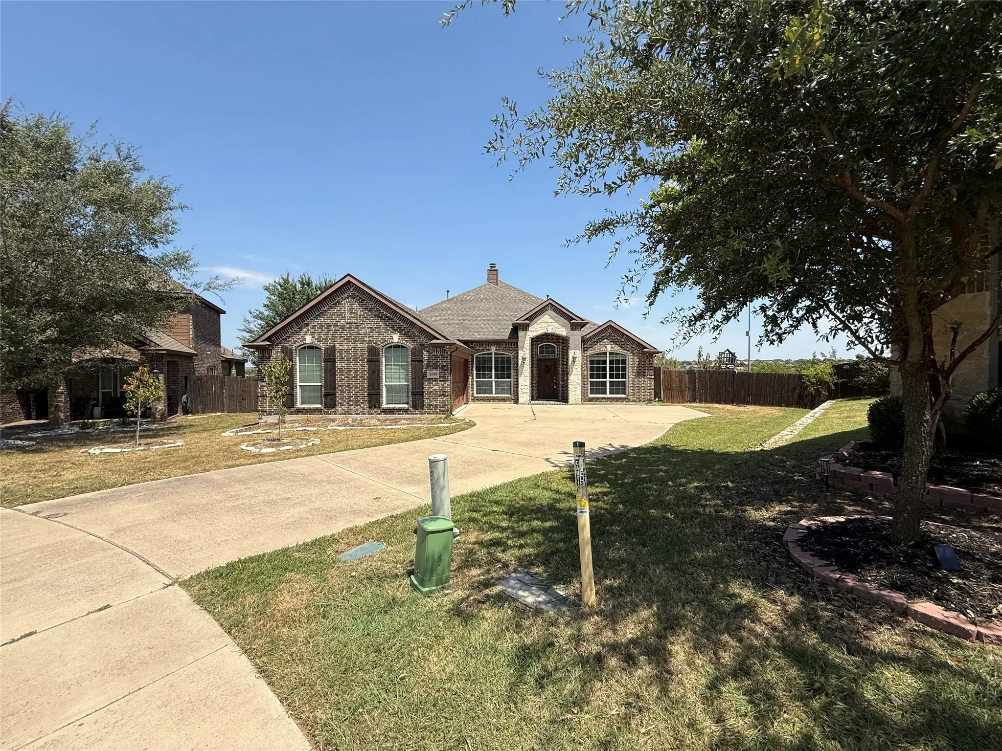Brick and stone facade with an arched entry, multiple gabled rooflines, and a curved concrete driveway