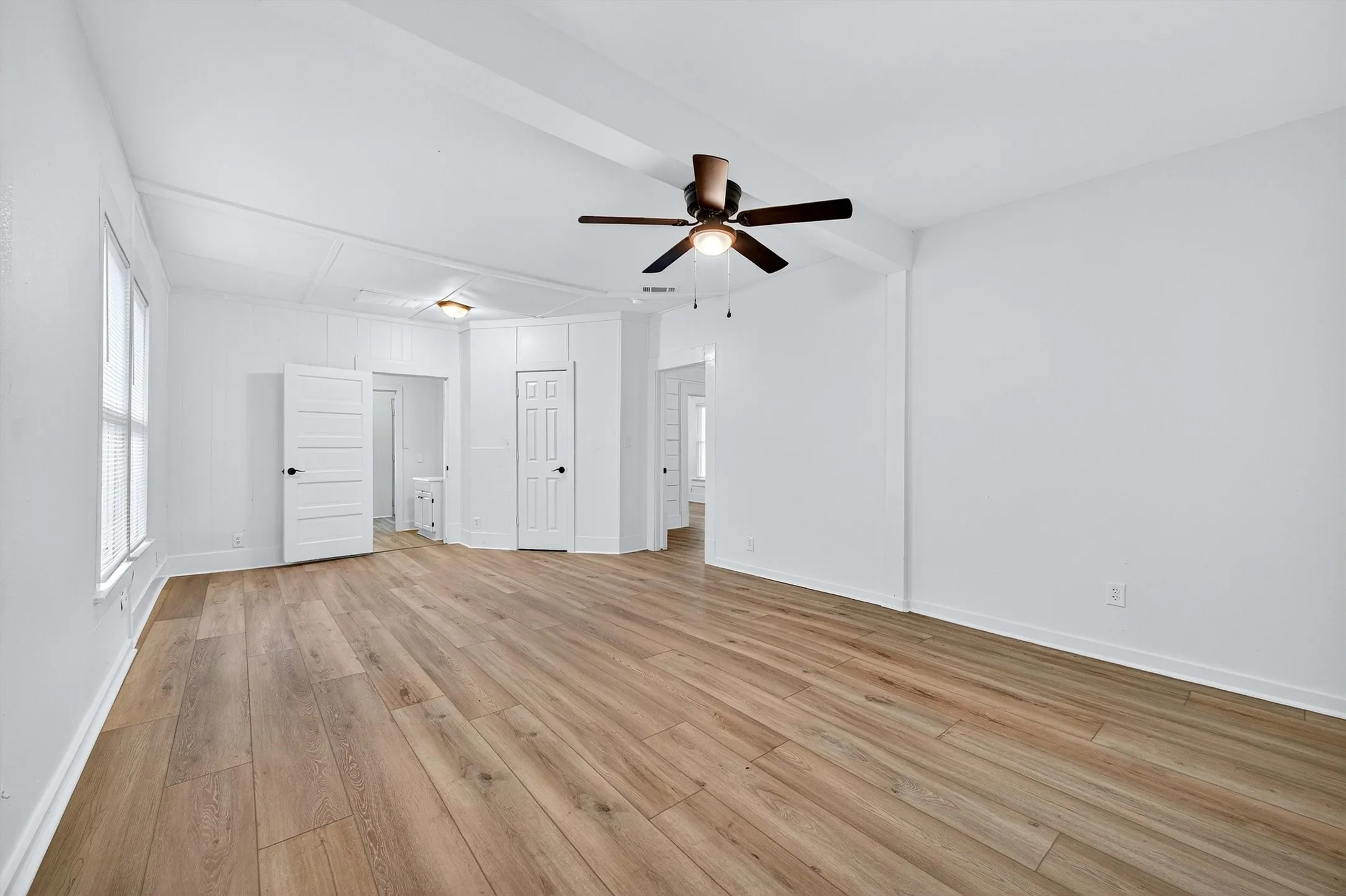 Unfurnished bedroom with light wood-style floors, ceiling fan, a closet, and ensuite bath