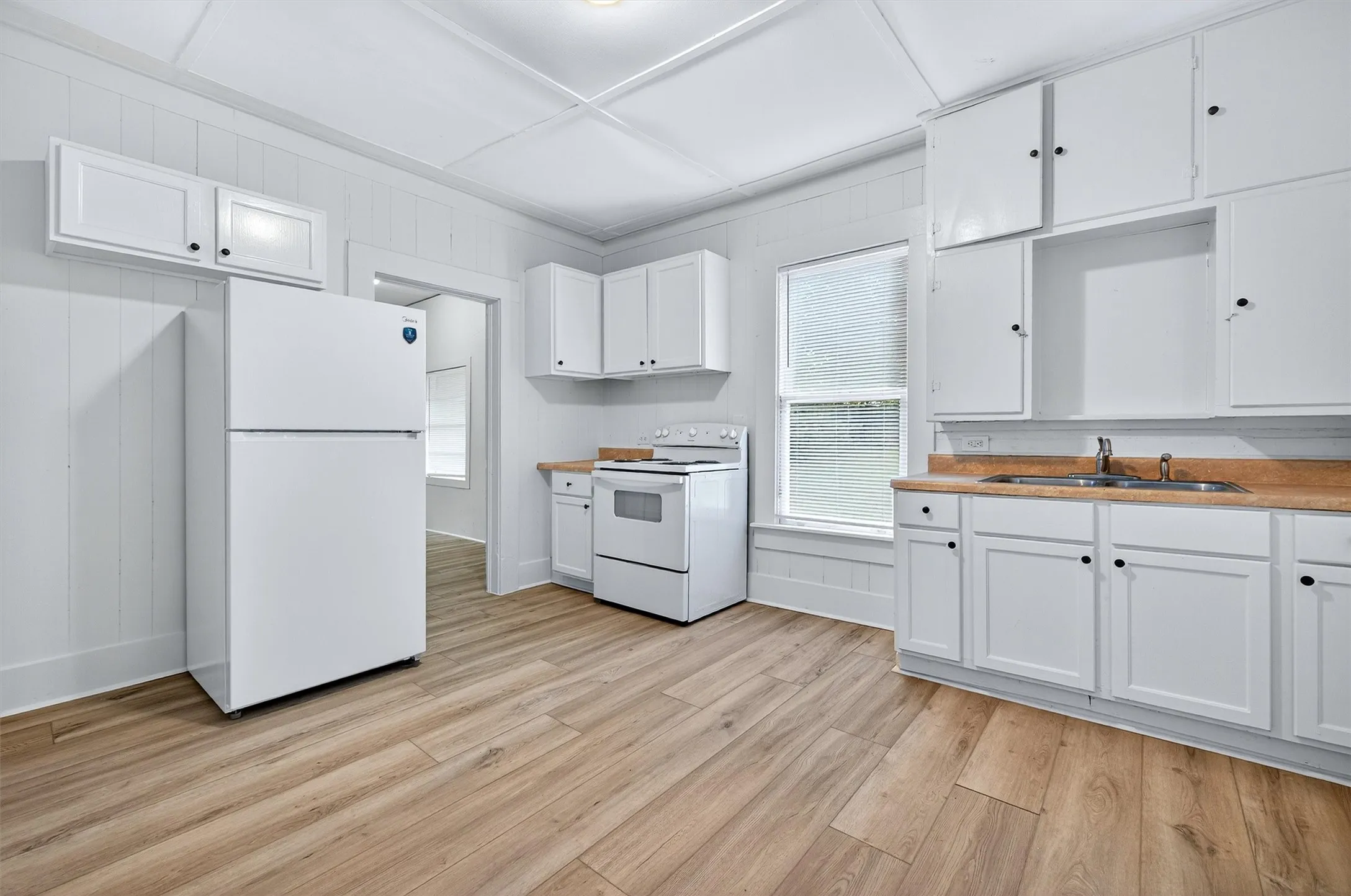 Kitchen featuring white appliances, white cabinetry, healthy amount of natural light, and light countertops