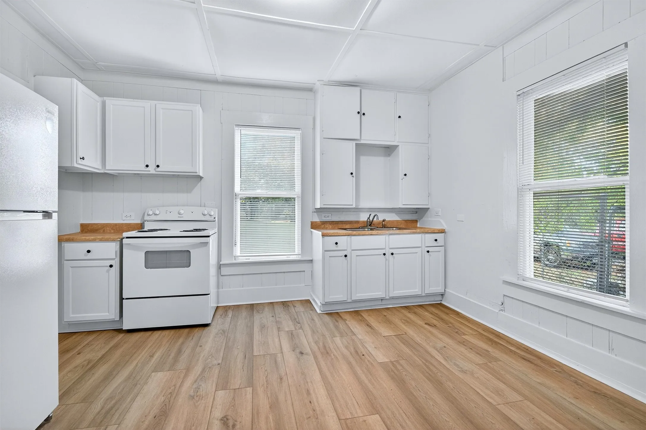 Kitchen with white appliances, white cabinetry, and light wood-type flooring