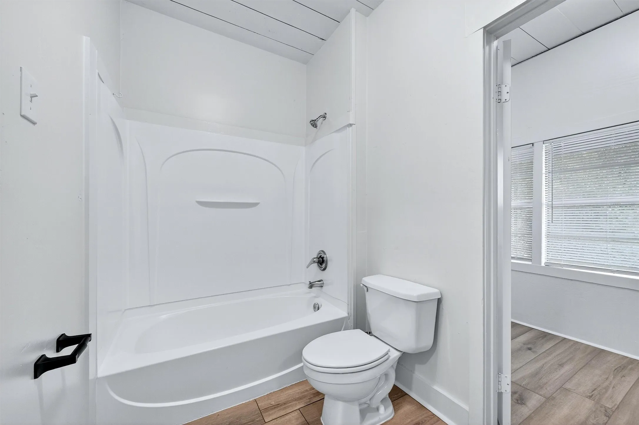 Bathroom with tub / shower combination and light wood finished floors