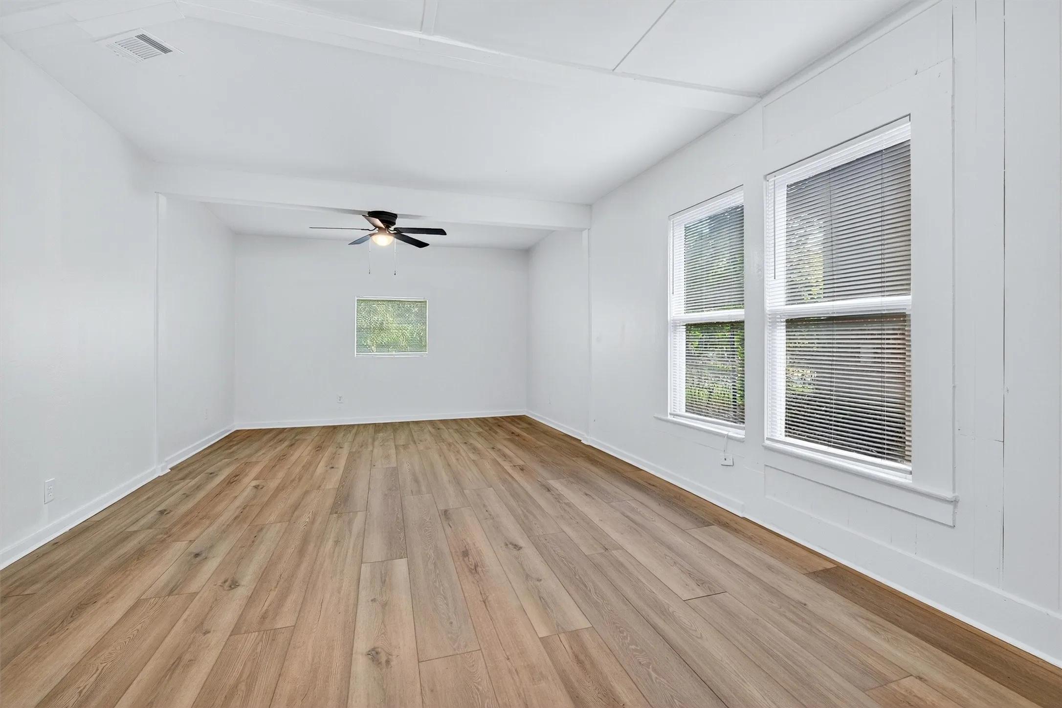 Spare room with light wood finished floors, beam ceiling, and ceiling fan