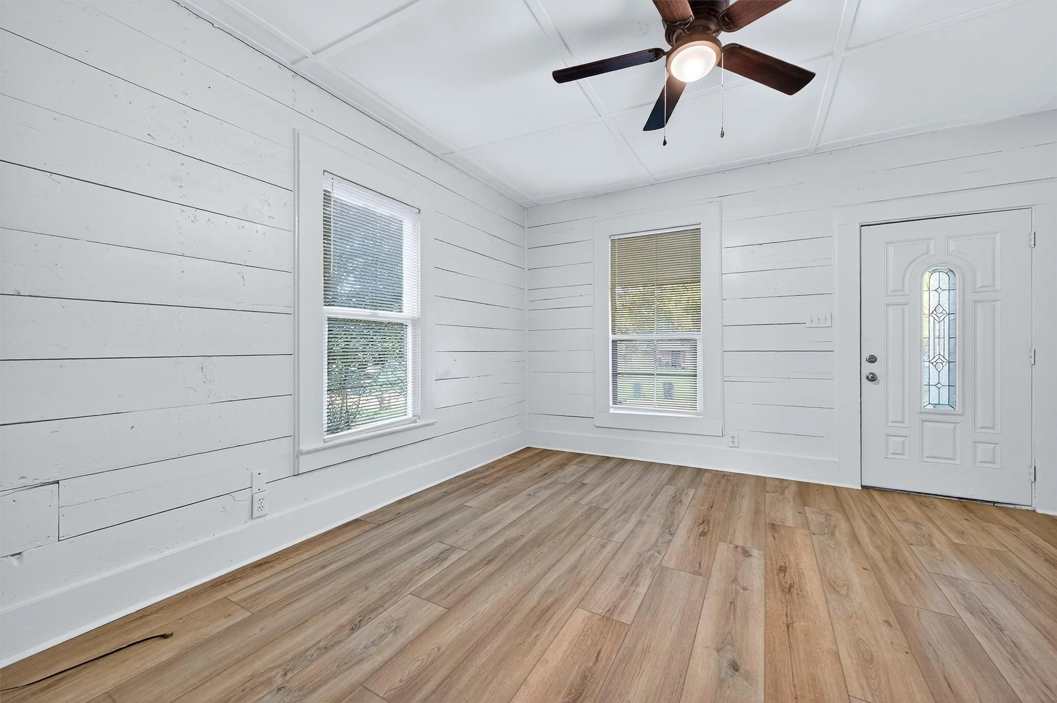 Entryway featuring plenty of natural light, light wood-type flooring, wooden walls, and ceiling fan
