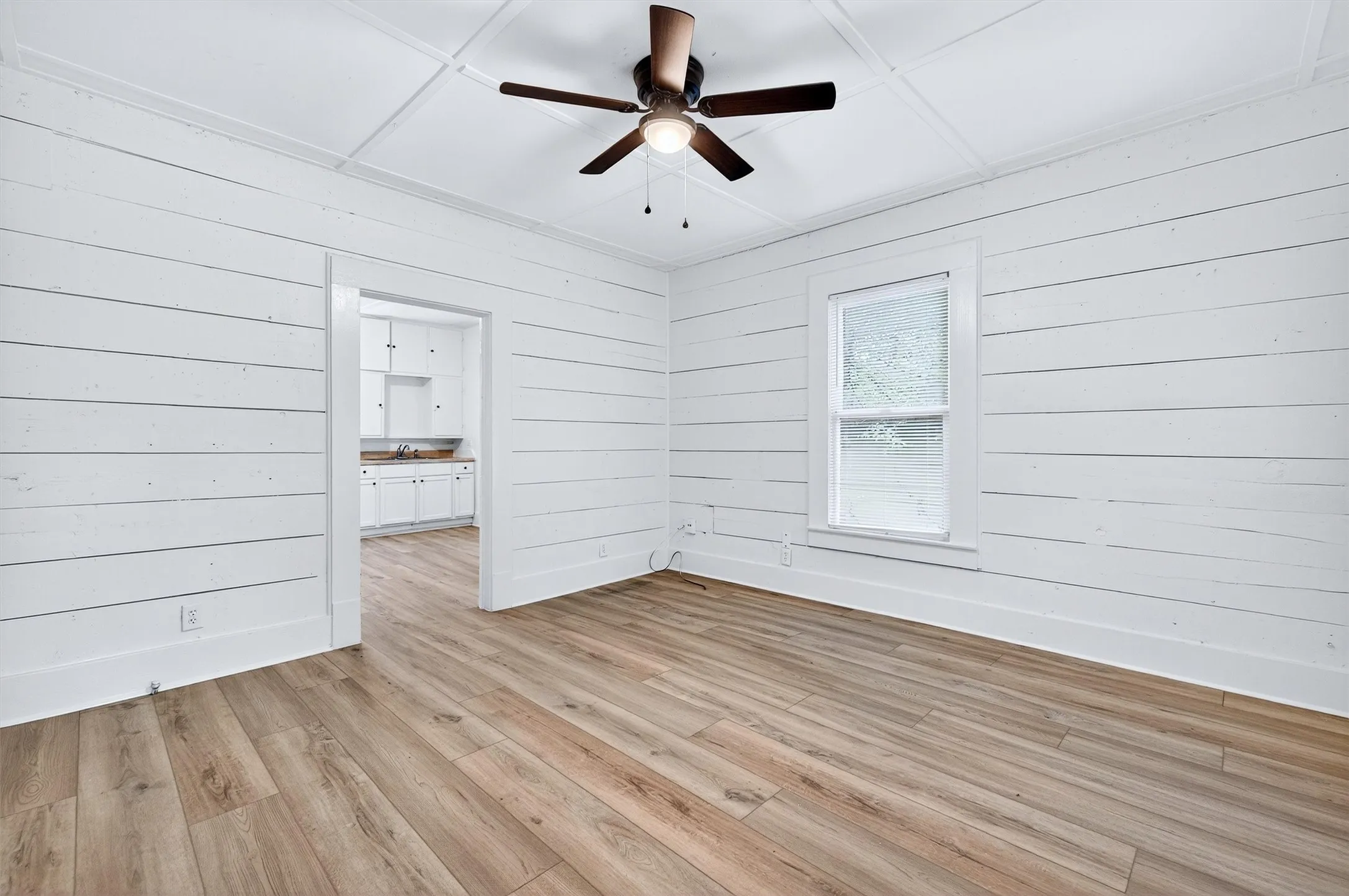Empty room featuring wooden walls, light wood-type flooring, and ceiling fan