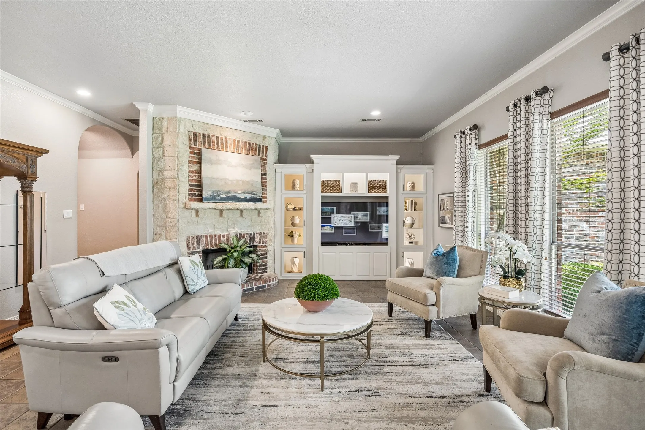 Custom cabinets, stone and brick fireplace and wall of windows overlooking backyard