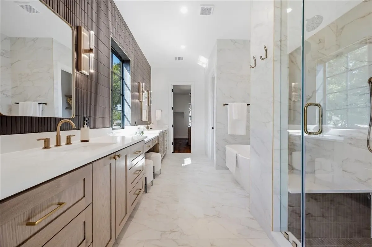 Double vanity with integrated sinks, wood-finish cabinetry, and brass hardware