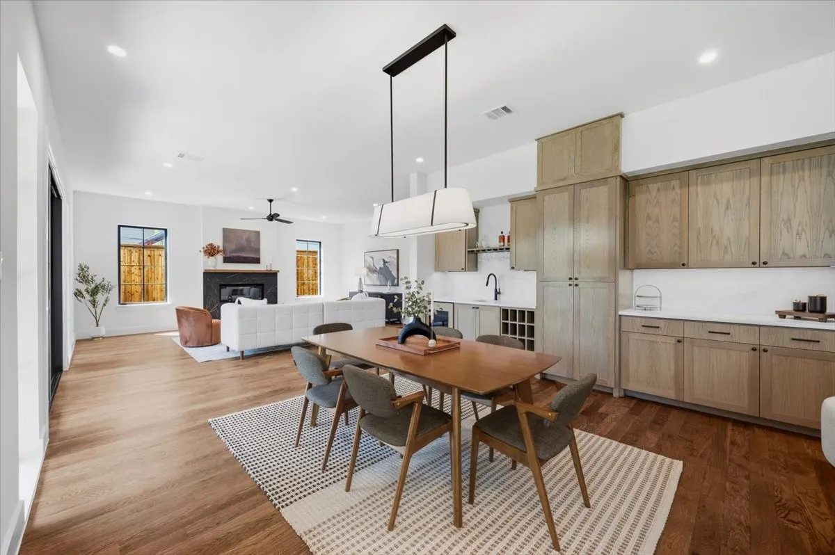 Hardwood flooring throughout, built-in dry bar with wine storage, recessed lighting, and a modern linear chandelier