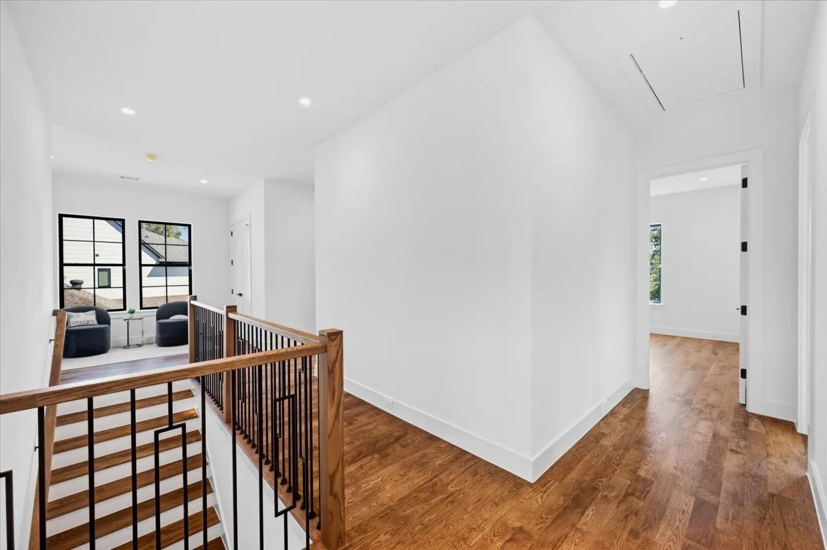 Hardwood flooring throughout, modern black-framed windows, recessed ceiling lighting, and a contemporary stair railing with wood newel posts