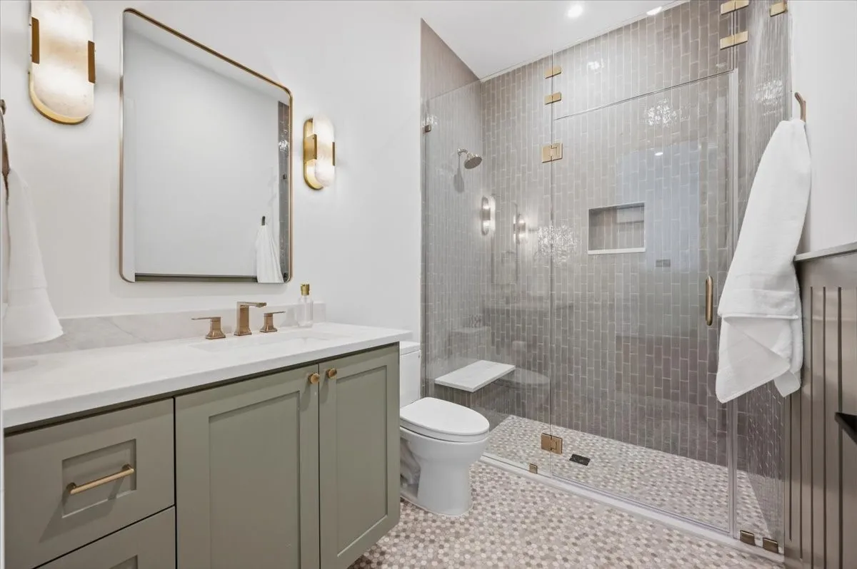 Glass-enclosed shower with subway tile surround, built-in shower niche, and integrated bench