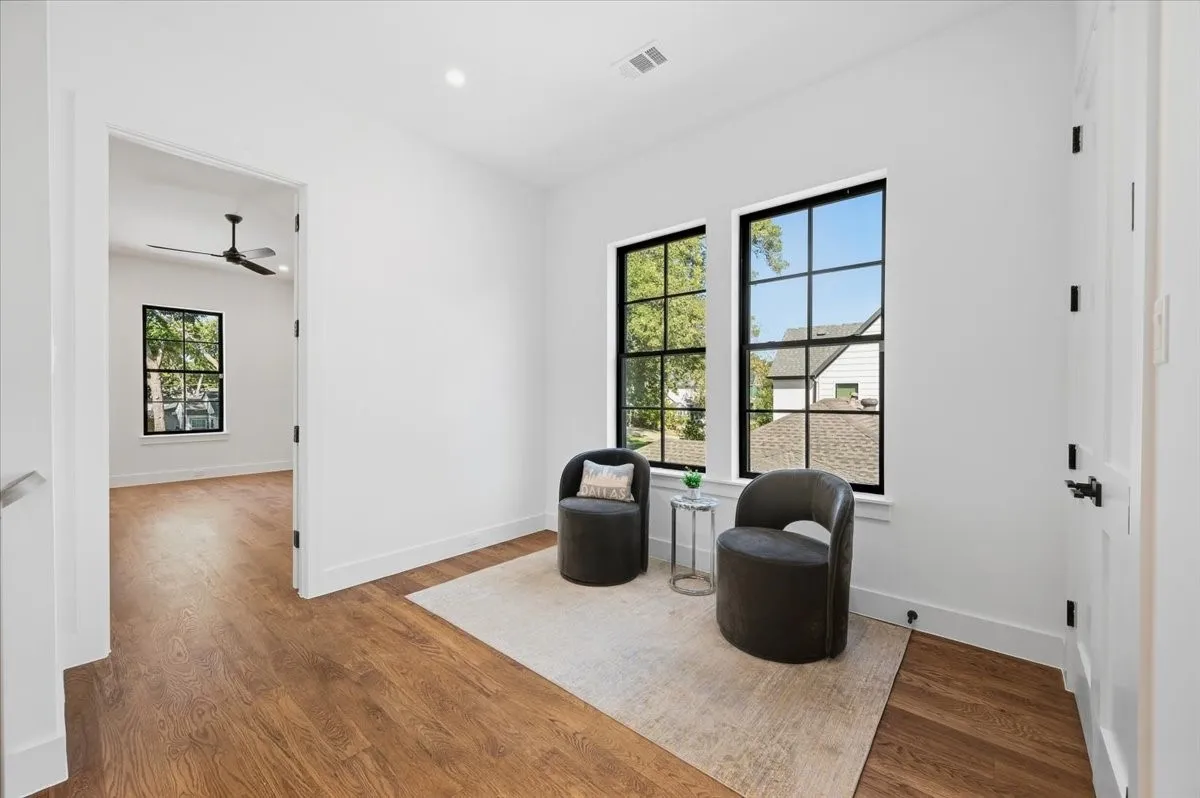 Expansive room featuring wood-finish flooring, white walls, and multiple grid-pattern windows