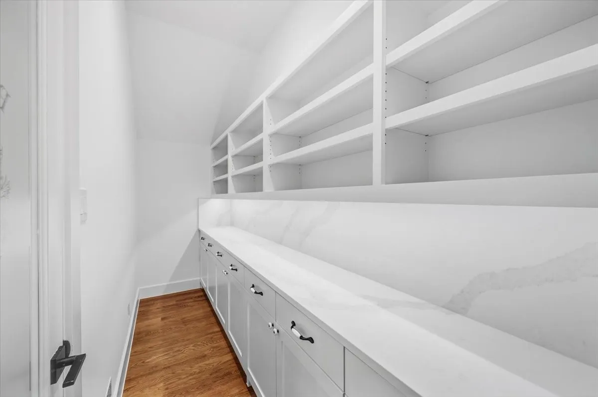 Built-in shelving, lower cabinetry with drawers, white countertop, white backsplash, and wood-finish flooring