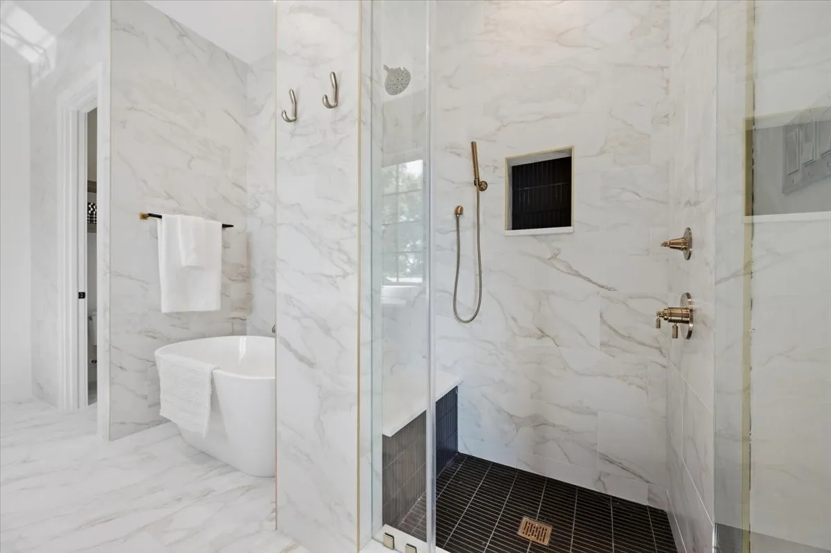 Freestanding soaking tub, walk-in shower with glass enclosure, integrated shower niche, and brushed brass fixtures