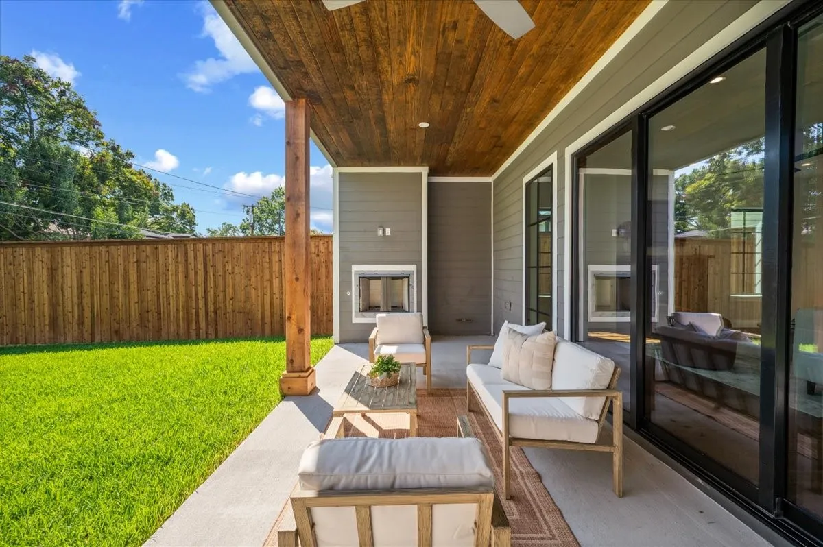 Covered patio with a wood-plank ceiling, ceiling fan, and built-in fireplace