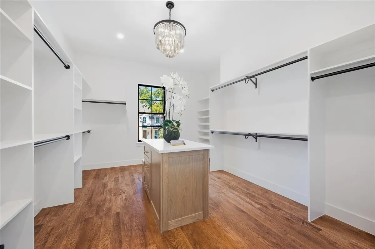 Hardwood flooring, custom built-in shelving, center island with stone countertop, recessed lighting, and a crystal chandelier