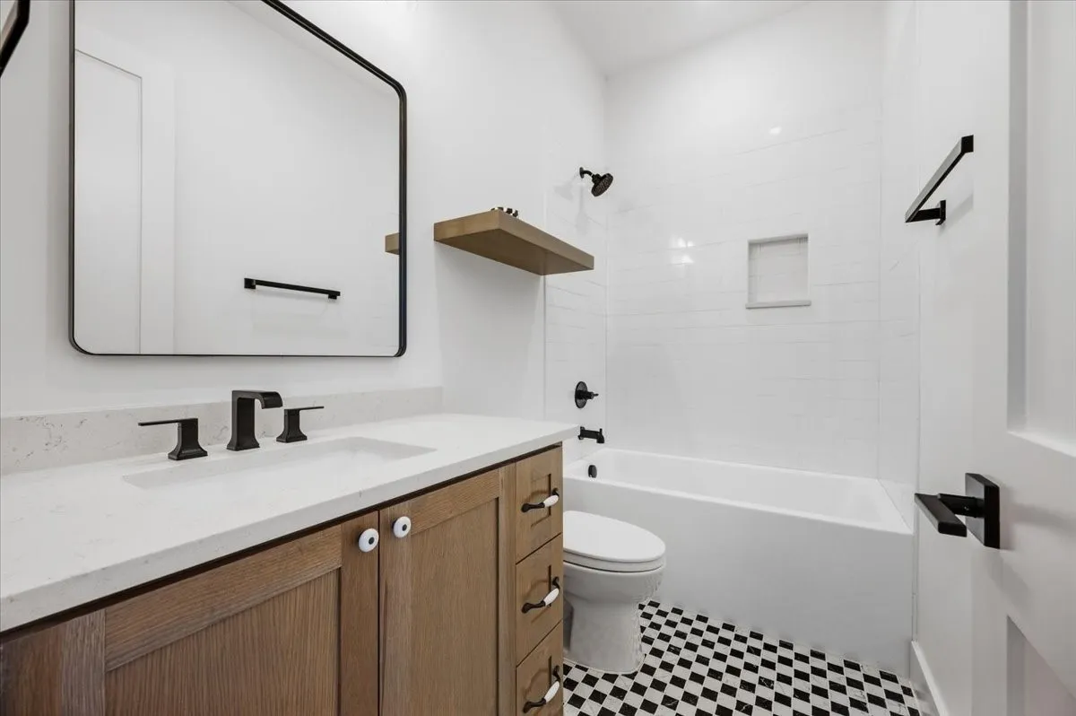 Bathroom with wood-finish vanity, white countertop, and matte black fixtures