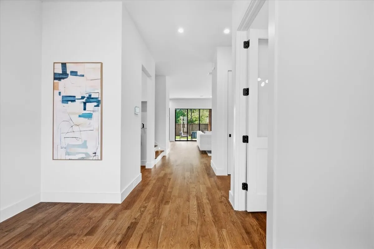 Hardwood flooring throughout, recessed lighting, and white walls