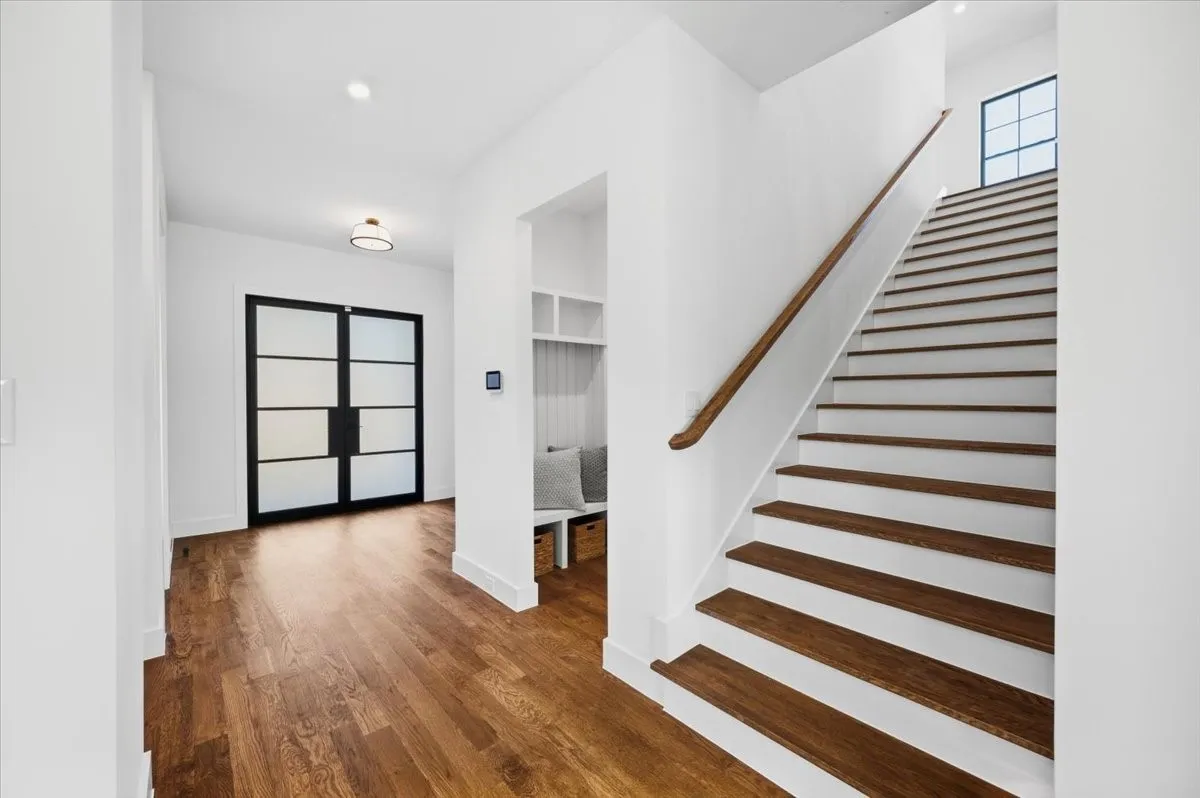 Hardwood-finish flooring, built-in cabinetry, integrated desk space, decorative wall paneling, and an expansive window