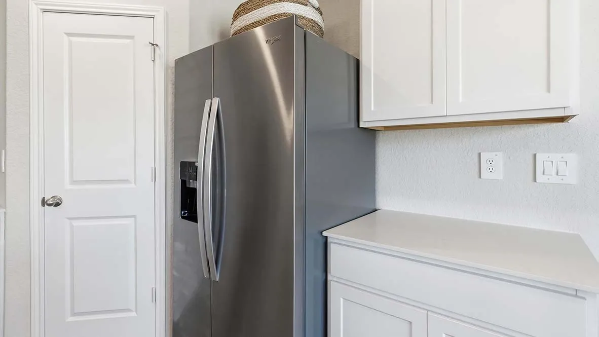 Stainless steel side-by-side refrigerator, white flat-panel cabinetry, and a light-colored countertop