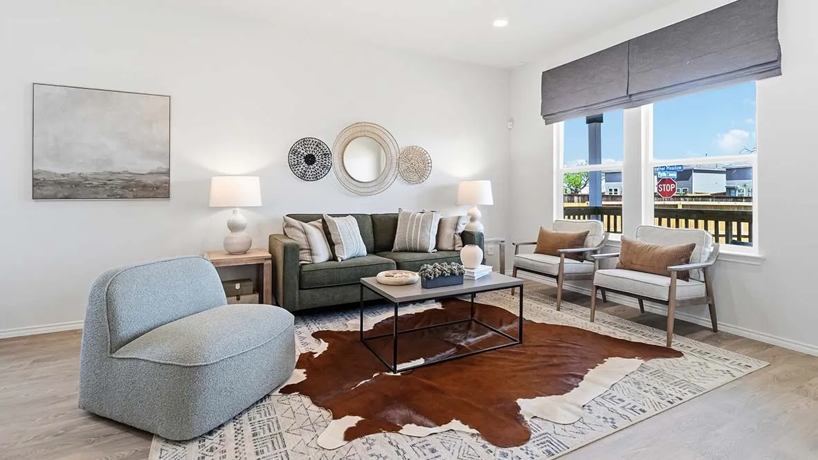 Spacious living area featuring light wood-finish flooring and ample natural light from large windows