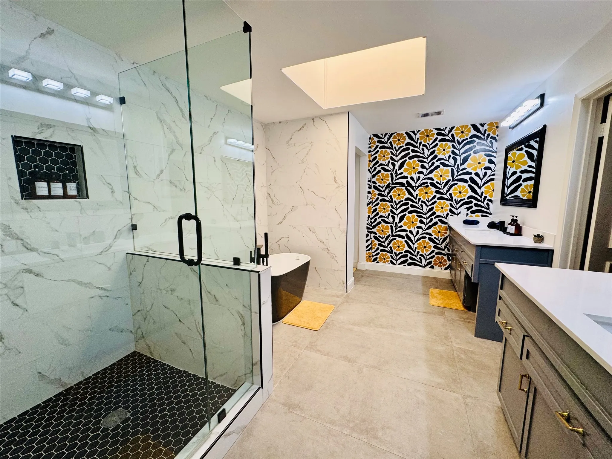 Glass-enclosed shower with black hexagon tile flooring and a built-in niche