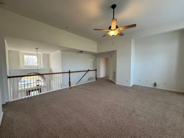 Spacious loft area featuring a ceiling fan with integrated lighting, broadloom carpeting, and an open railing overlooking the lower level