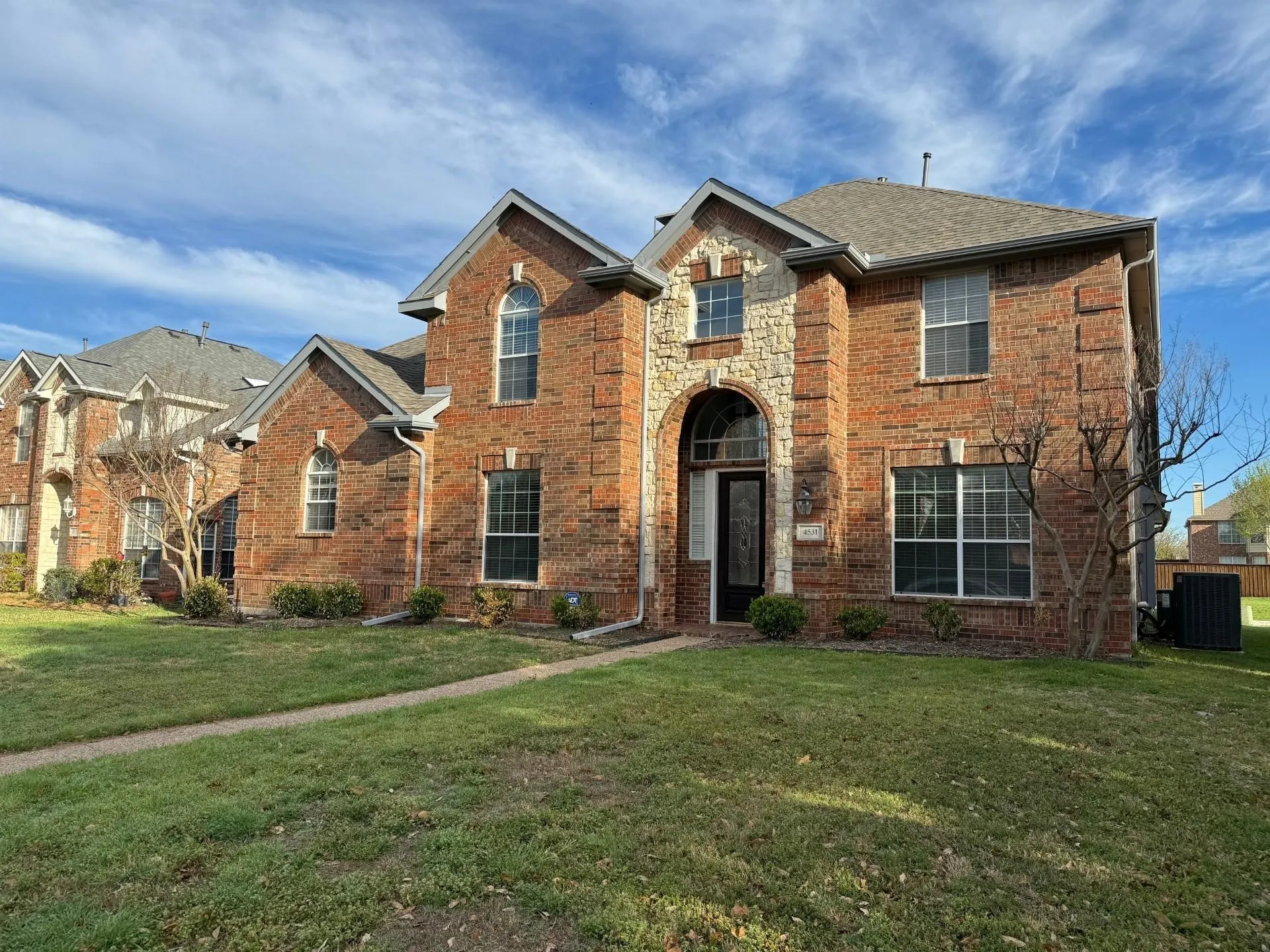 Brick exterior with stone accents, arched entryway, and multiple gables